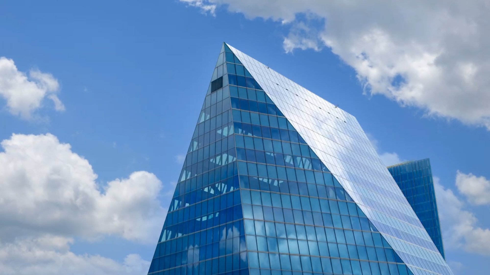 Glass office building against blue sky with clouds