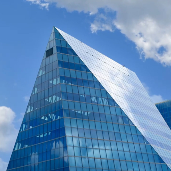 Glass office building against blue sky with clouds