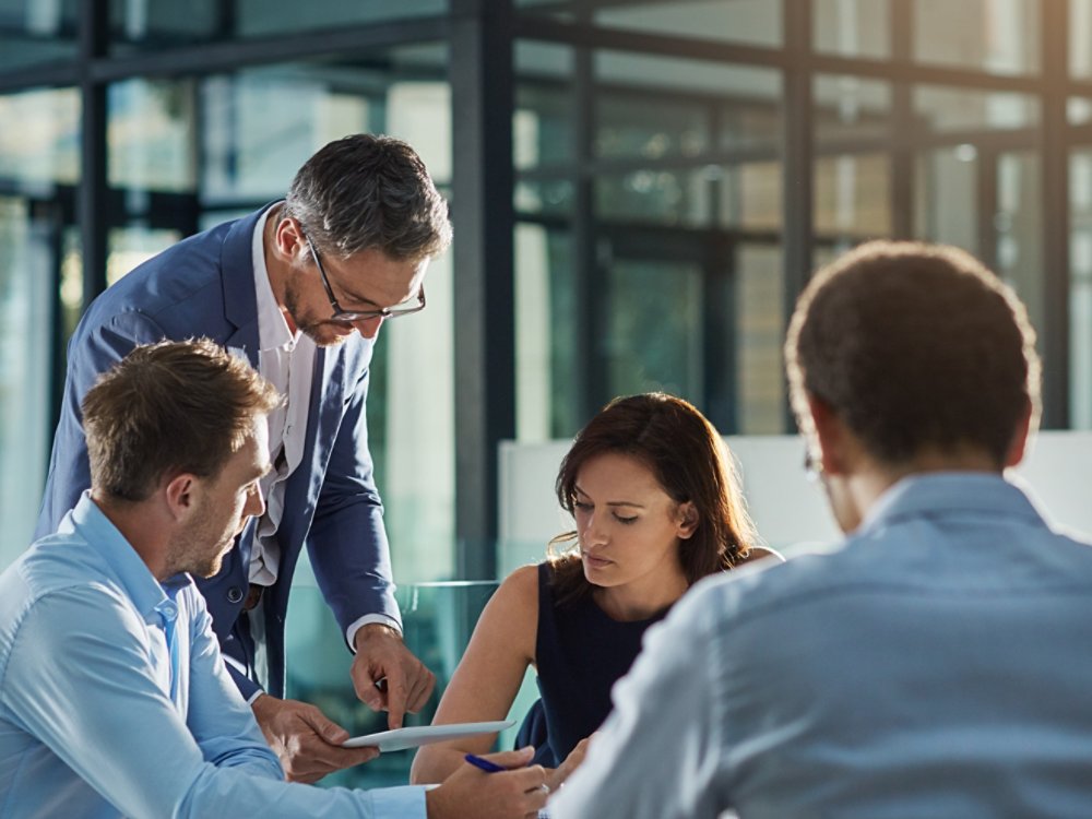 Man, tablet and business people in meeting for coaching, goals and mission at desk for discussion. Teamwork, woman and strategy for vision, collaboration or innovation in financial company with coach.