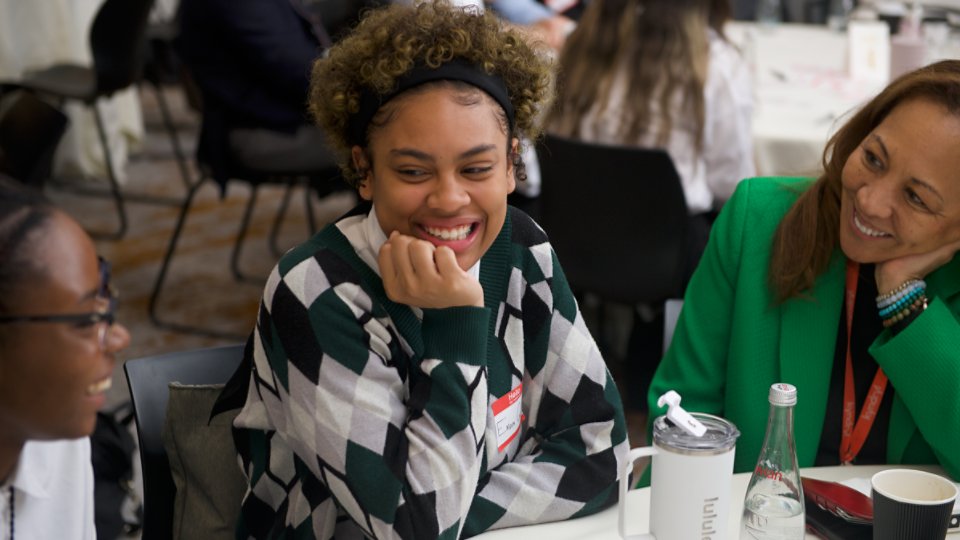 Two female black students and a mentor smiling at an IT industry Career Day in NYC