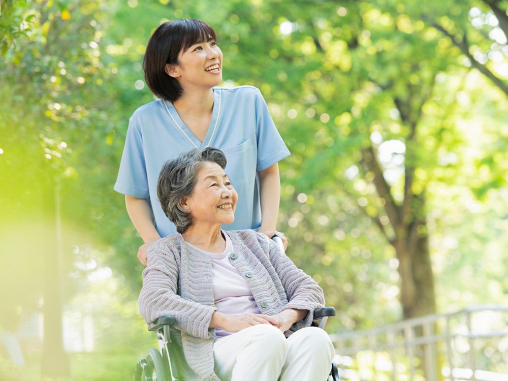 caretaker with woman in wheelchair in the woods