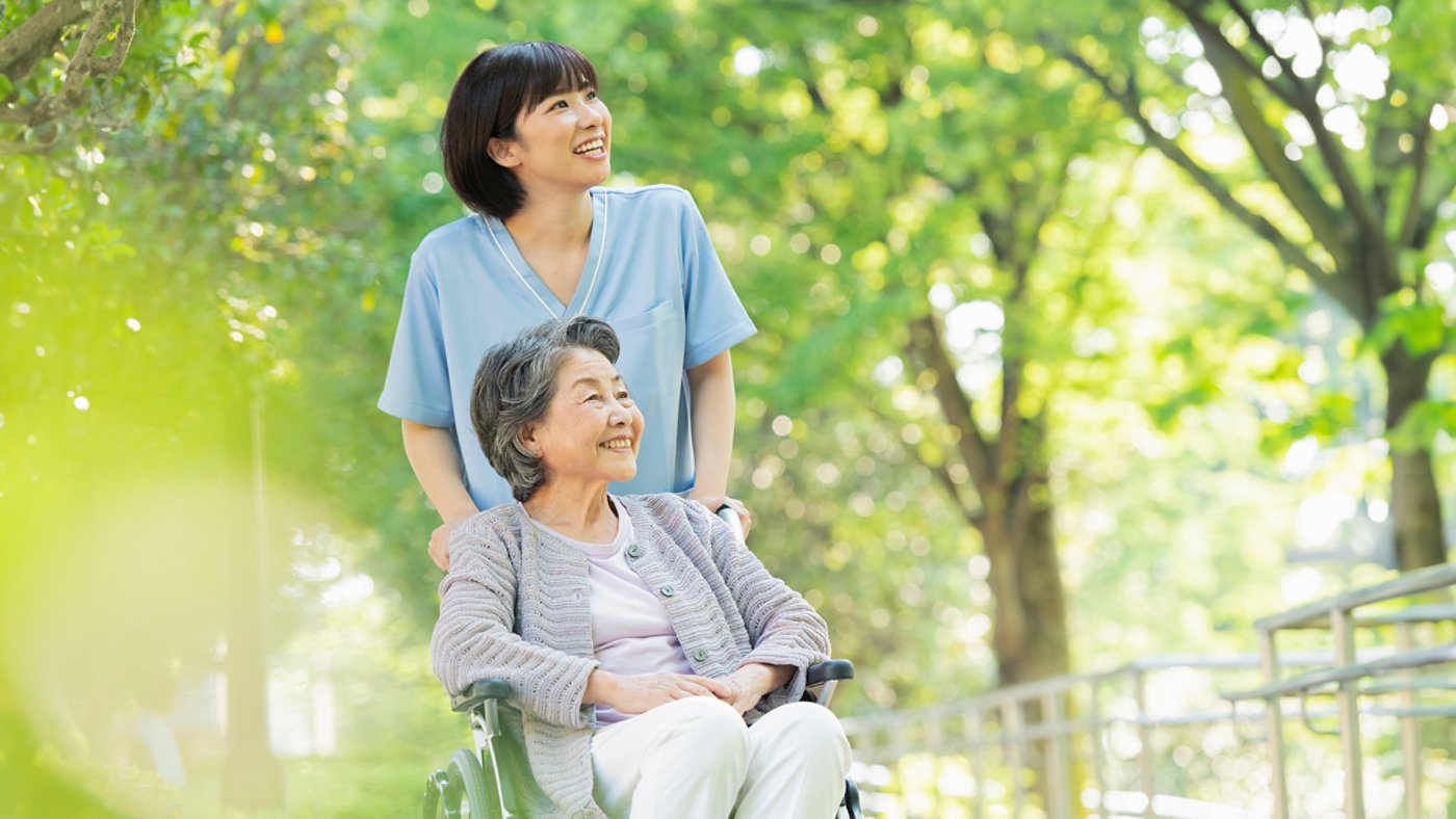 caretaker with woman in wheelchair in the woods