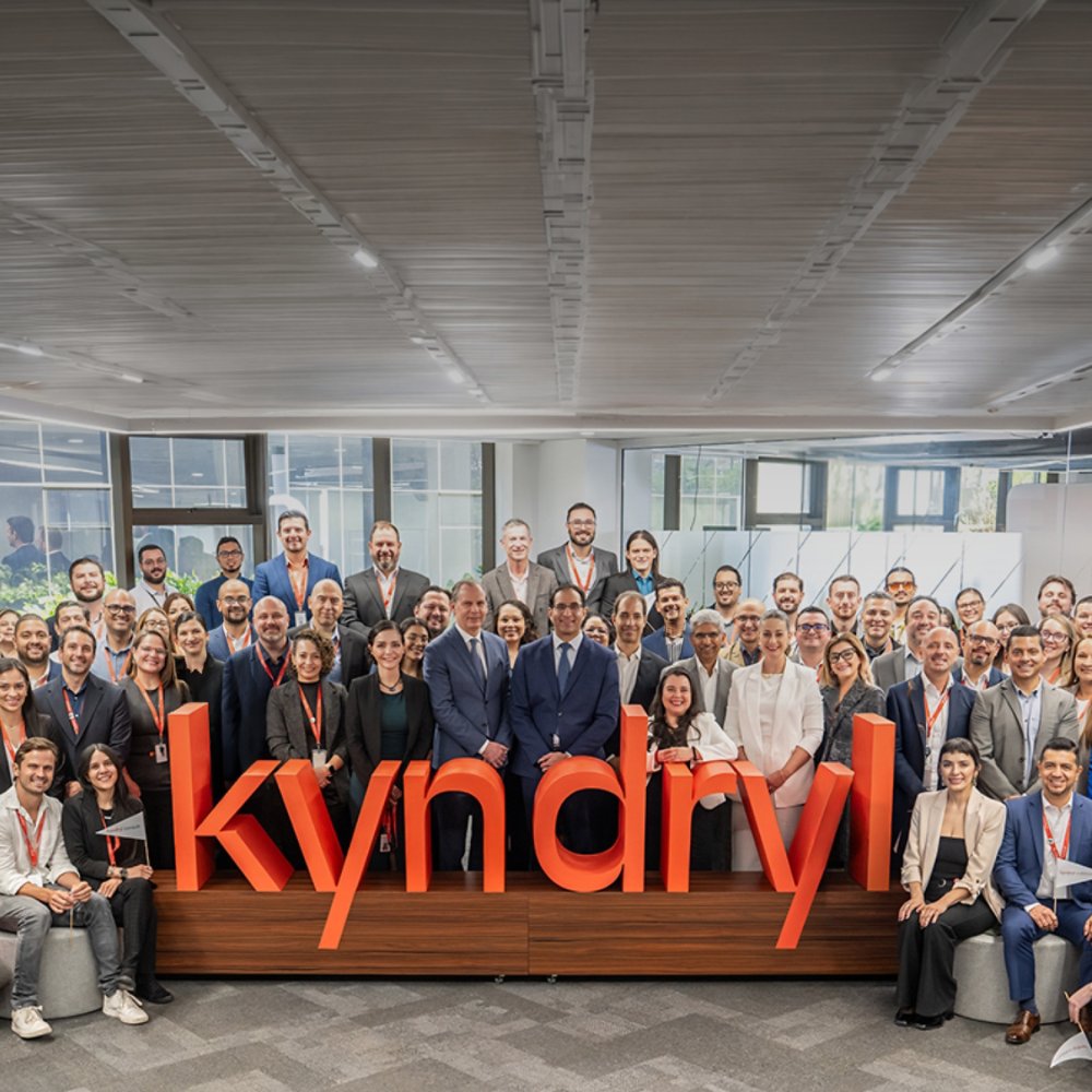 Kyndryl employees standing around the a 3D sculpture of the logo