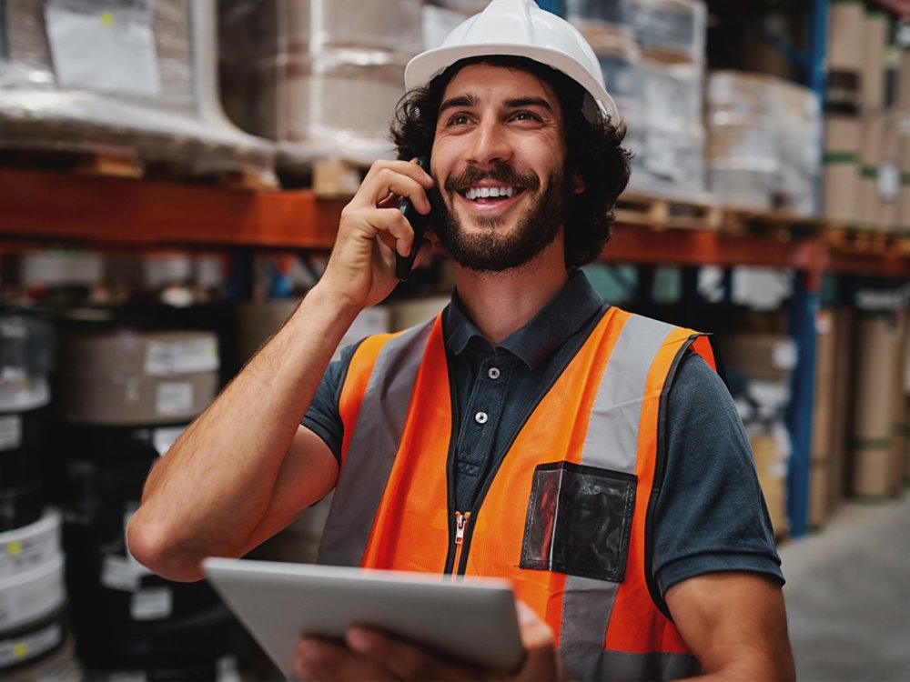 Cheerful supervisor holding digital tablet while talking on phone