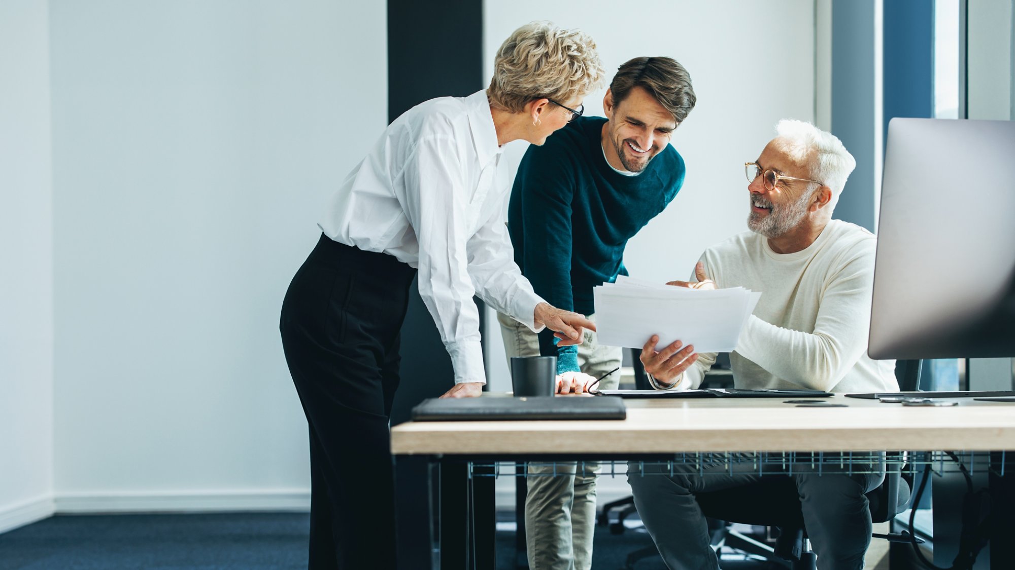 Three business people huddling and discussing a document in an office. Group of business professionals contributing their ideas and expertise as they collaborate on a project for their startup.