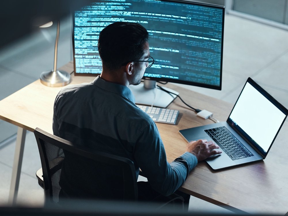 Man, programmer and coding at night on laptop mockup screen for networking, malware or software at the office. Male person, coder or developer working late in computer display in problem solving.