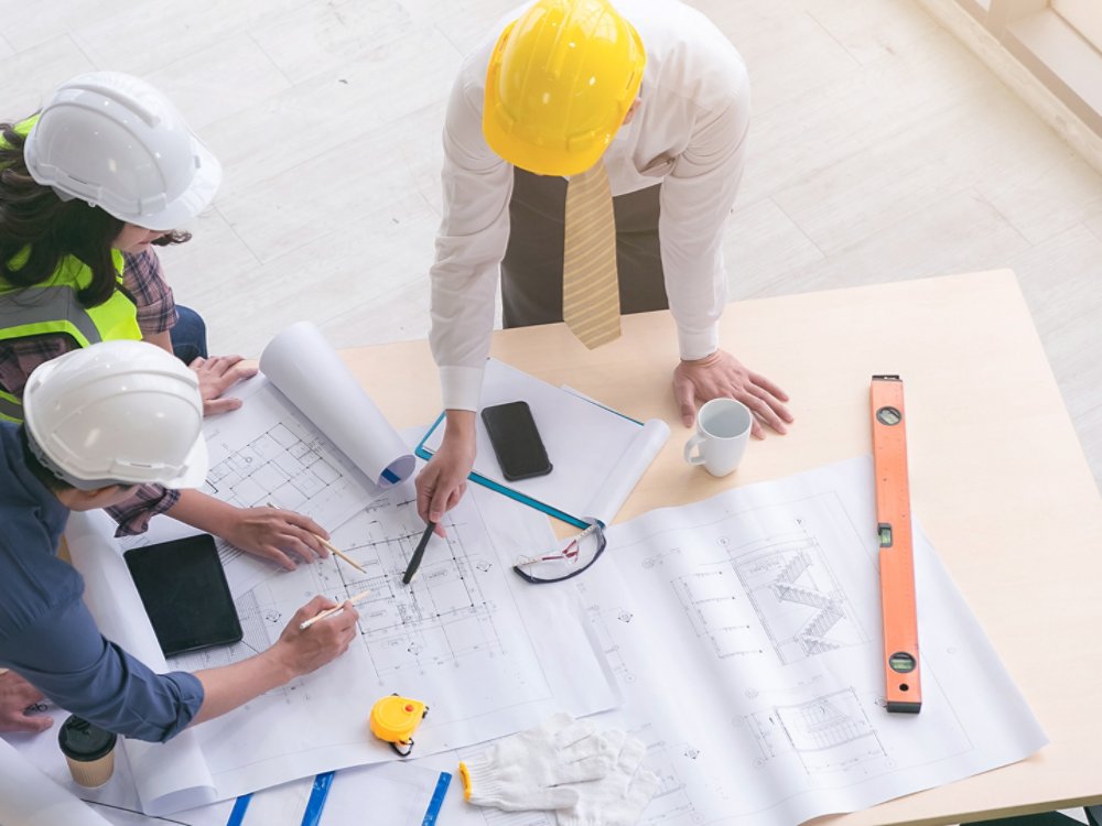 Team of engineers and architects working, planing, measuring layout of building blueprints in construction site. top view