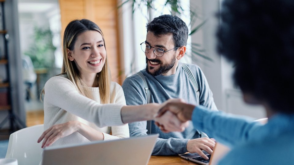 young couple shaking hands with banker