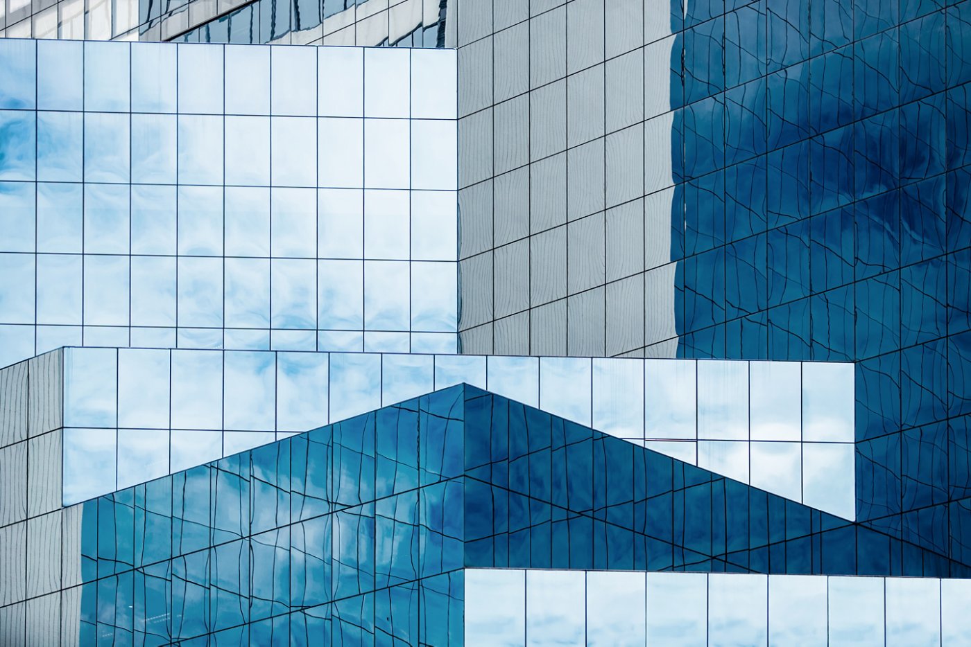 Blue sky and clouds reflecting in windows of modern office building