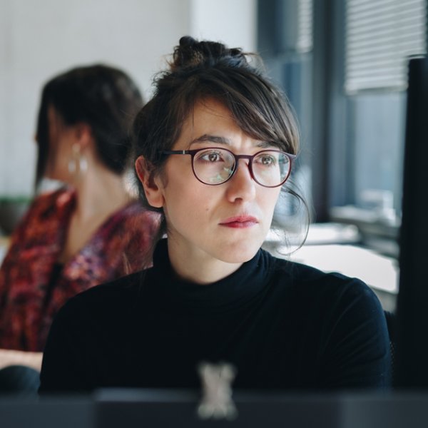 Portrait of  confident businesswoman working on computer in creative office. Coworkers in the background.