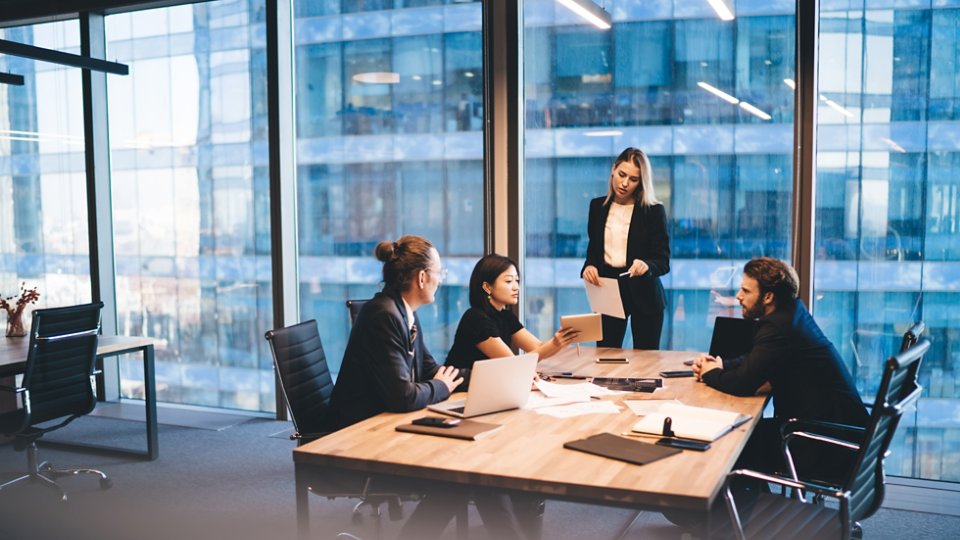 From above of multiethnic executive managers in classy outfit gathering at table and sharing ideas during meeting in modern workplace