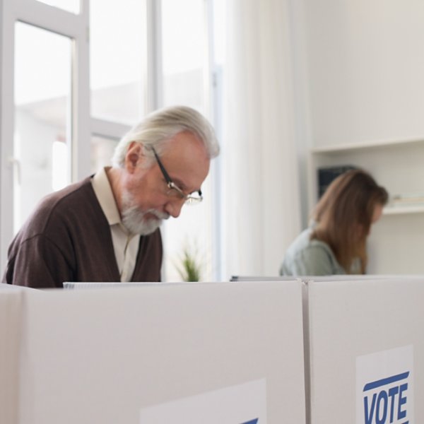 Concentrated men and women are reading information on election ballots before casting their votes