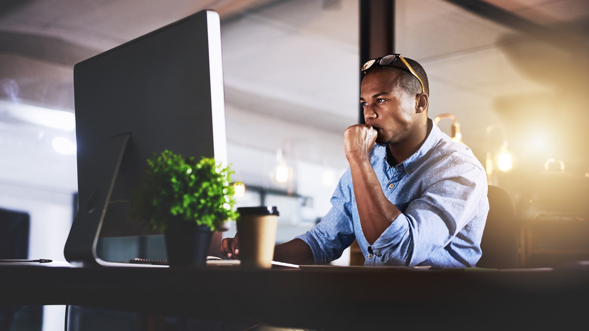 Thinking, computer and business black man in office for website, research and reading news at night. Startup, developer and worker online for software update, networking and working on web design.