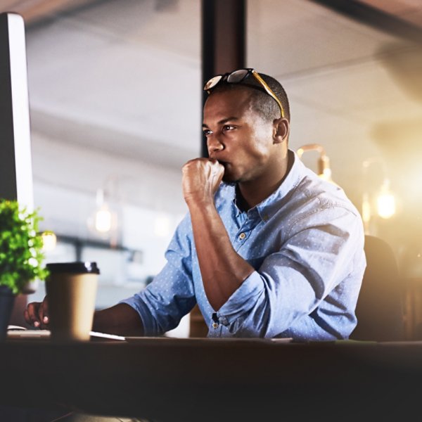 Thinking, computer and business black man in office for website, research and reading news at night. Startup, developer and worker online for software update, networking and working on web design.