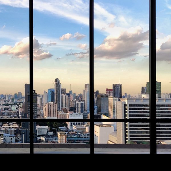 silhouette outline of women tourist taking pictures of city skyline from an observatory. sunset at modern urban business district. steel frame rose windows architectural element design.