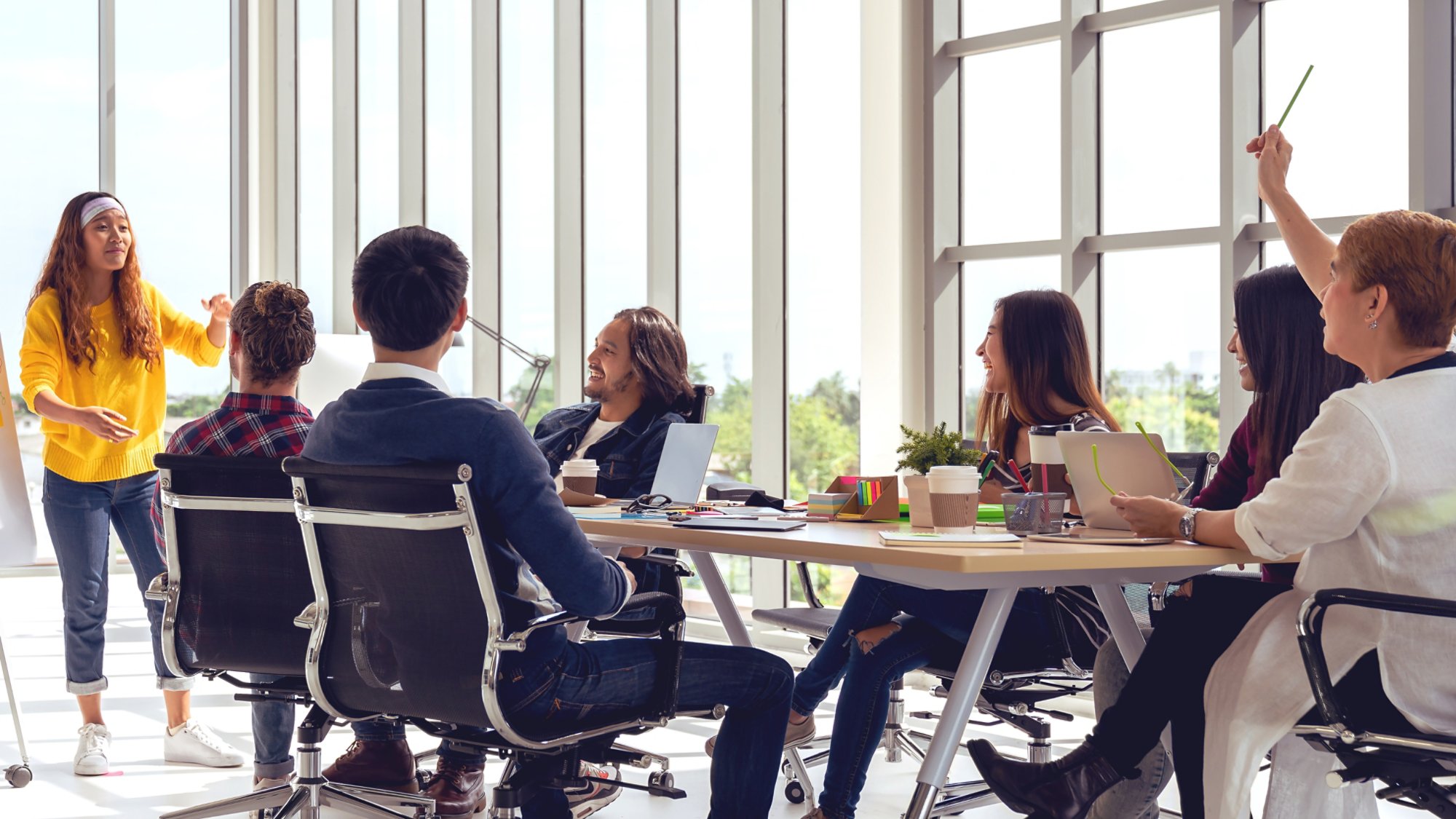 Young asian creative hipster female leader standing and making presentation at modern office happy talking and brainstorming idea with teamwork. Casual asian people business meeting workshop concept.