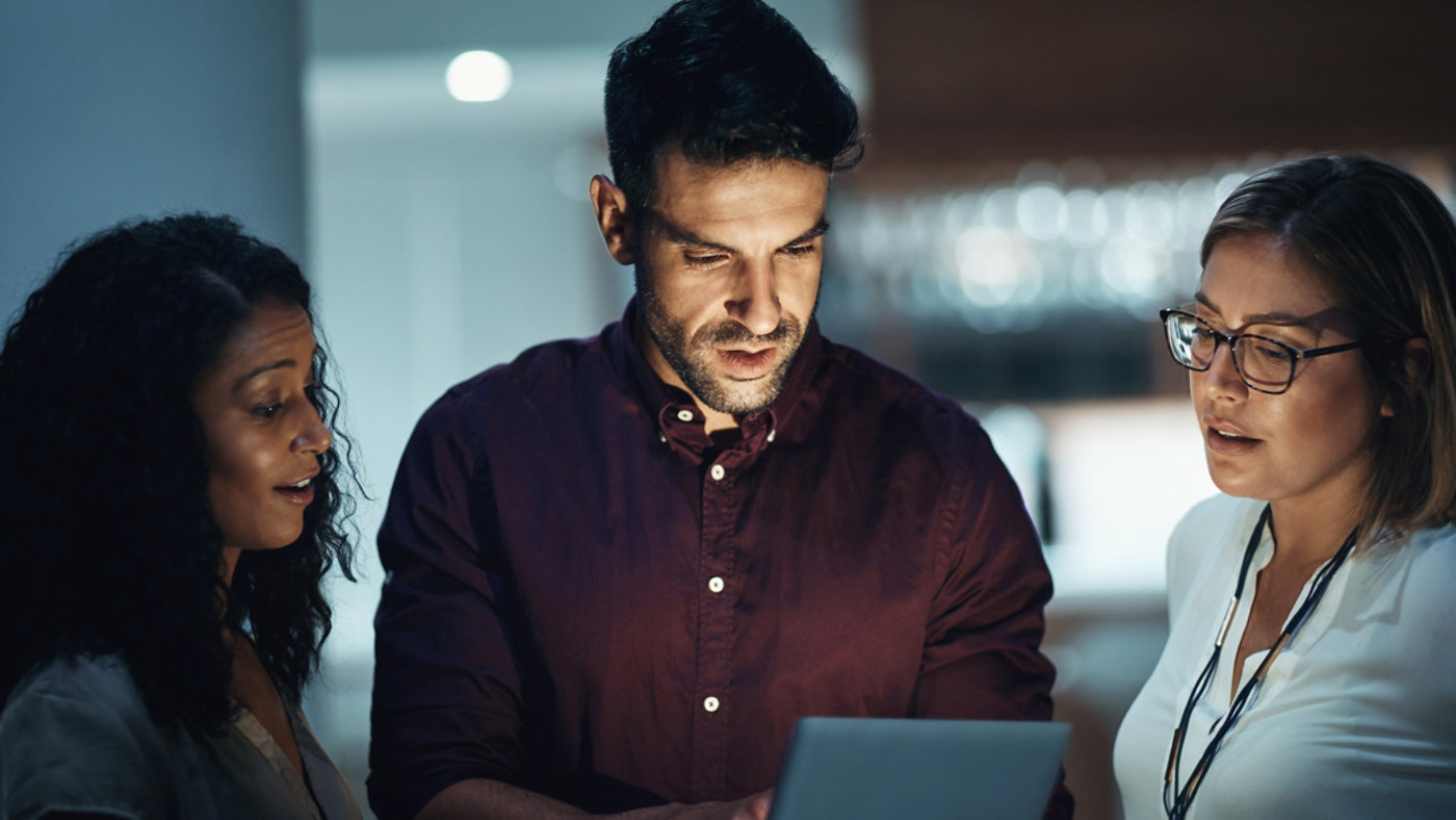 Shot of a group of colleagues using a digital tablet together during a late night at work.