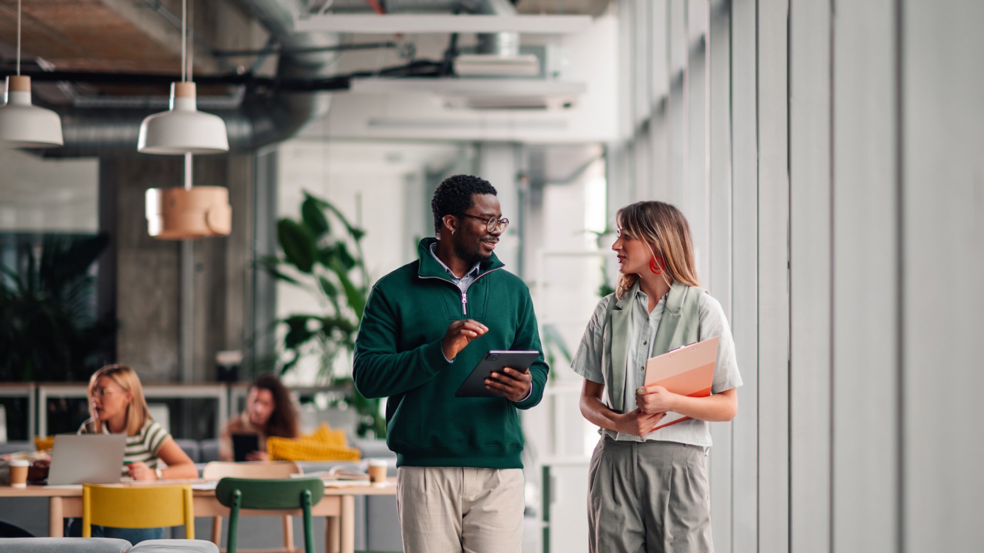 Diverse business colleagues walking, talking, and working together in an open plan office, demonstrating teamwork and collaboration