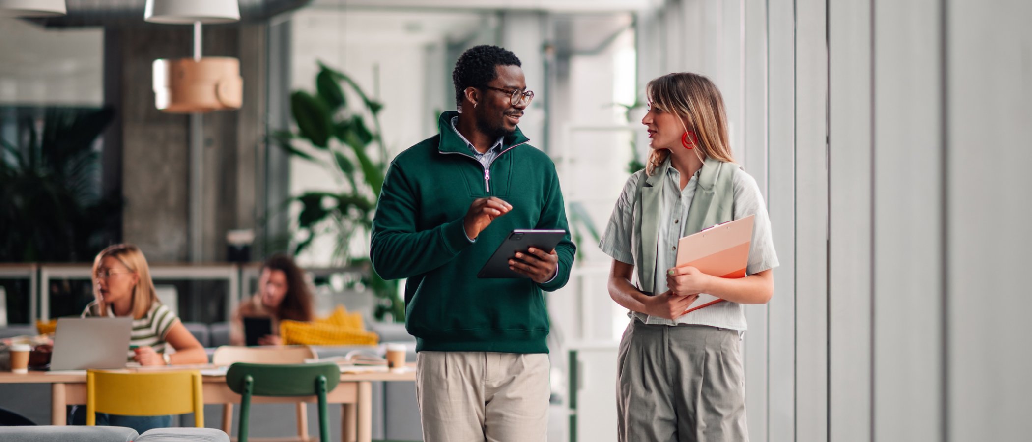 Diverse business colleagues walking, talking, and working together in an open plan office, demonstrating teamwork and collaboration