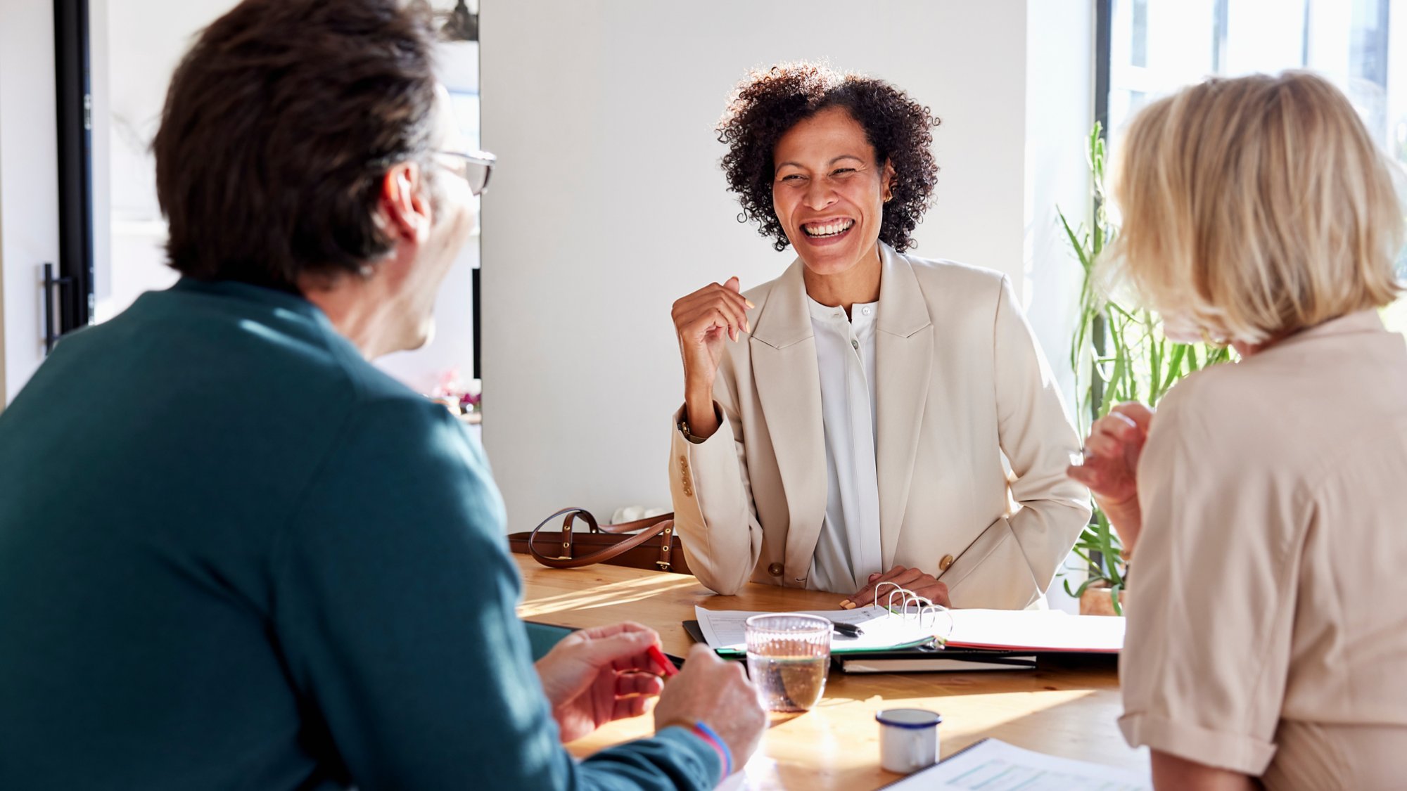 Smiling financial advisor manager speaking with couple while sitting at table and discussing home loan insurance policy