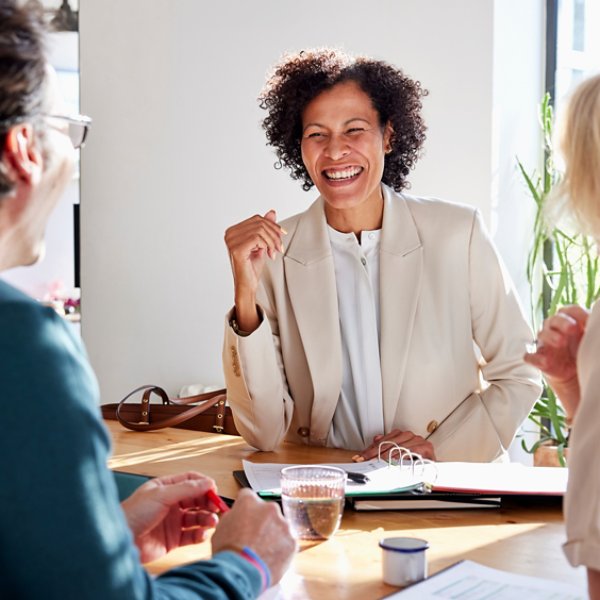 Smiling financial advisor manager speaking with couple while sitting at table and discussing home loan insurance policy