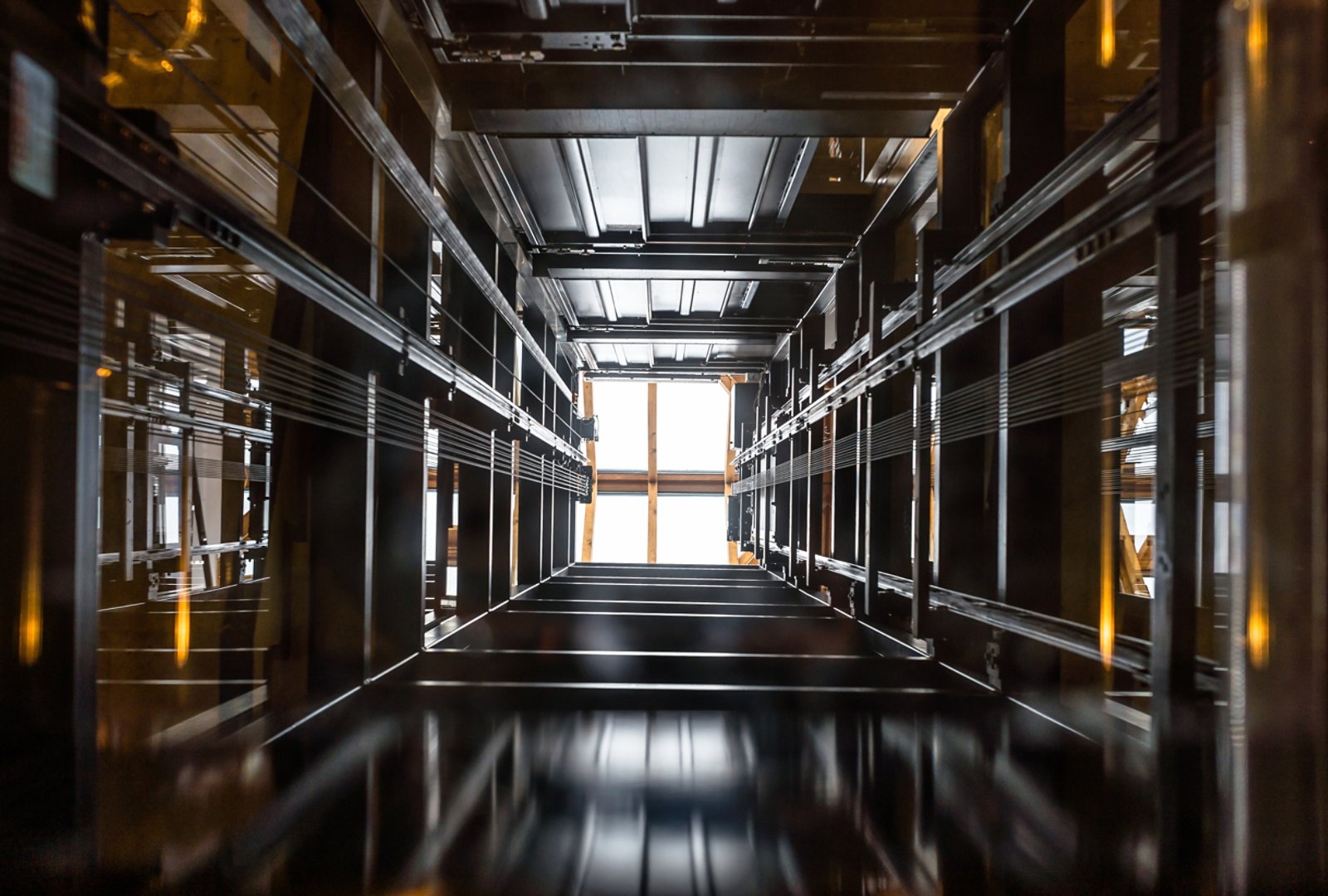 The passenger lift shaft seen from the glass cabin, a glazed roof at the top.