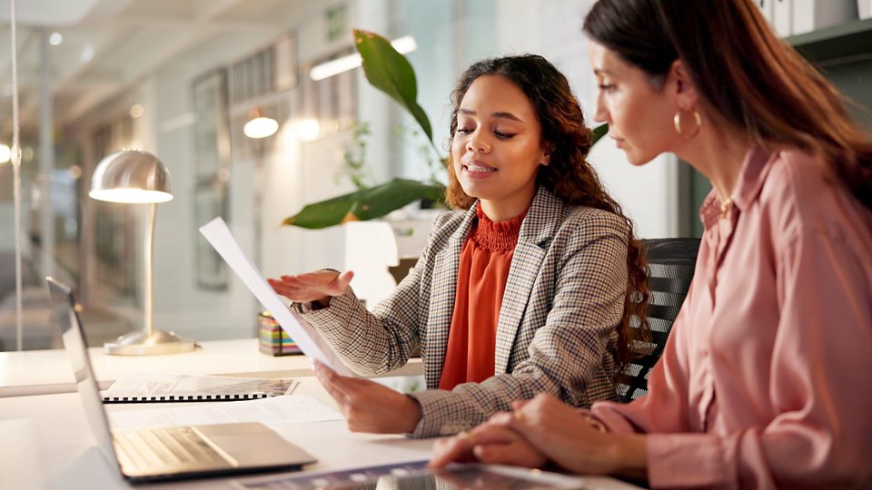 Planning, reading and financial advisor with client for document, investment discussion and tips. Business office, women team and talking with paperwork for policy review, laptop or corporate meeting.
