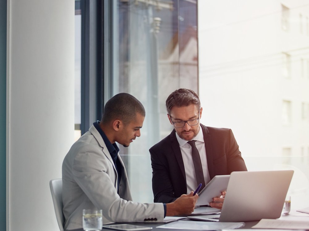 Tablet, laptop and business men planning in conference room meeting, teamwork and discussion of corporate data. Professional people or partner talking, review or report analysis on digital technology.