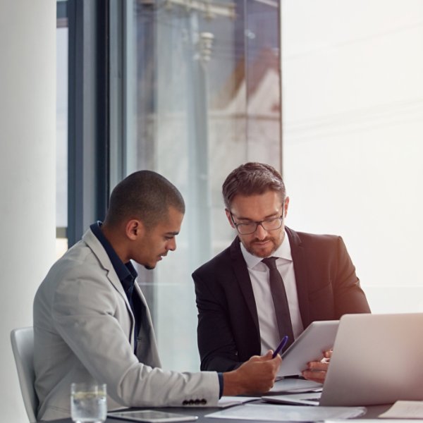 Tablet, laptop and business men planning in conference room meeting, teamwork and discussion of corporate data. Professional people or partner talking, review or report analysis on digital technology.