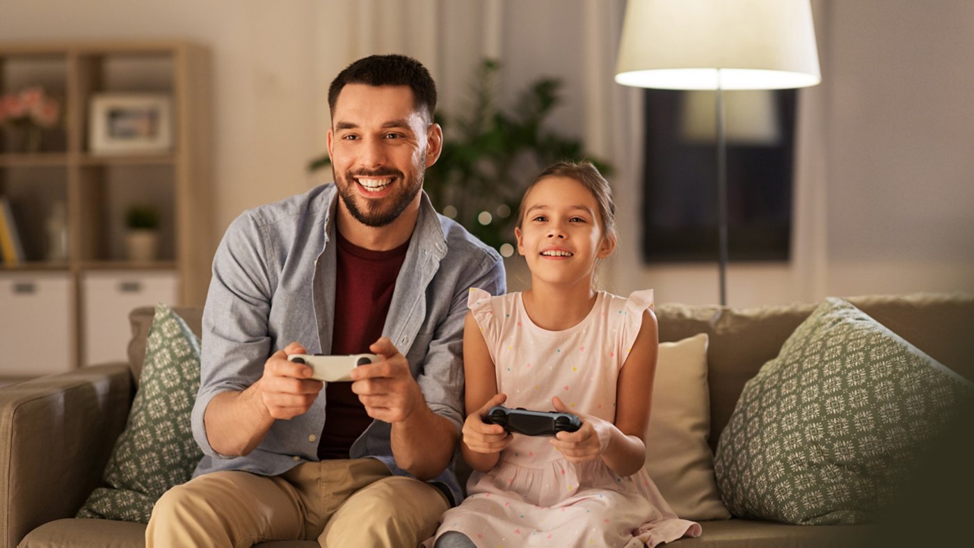 family, gaming and entertainment concept - happy father and little daughter with gamepads playing video game at home