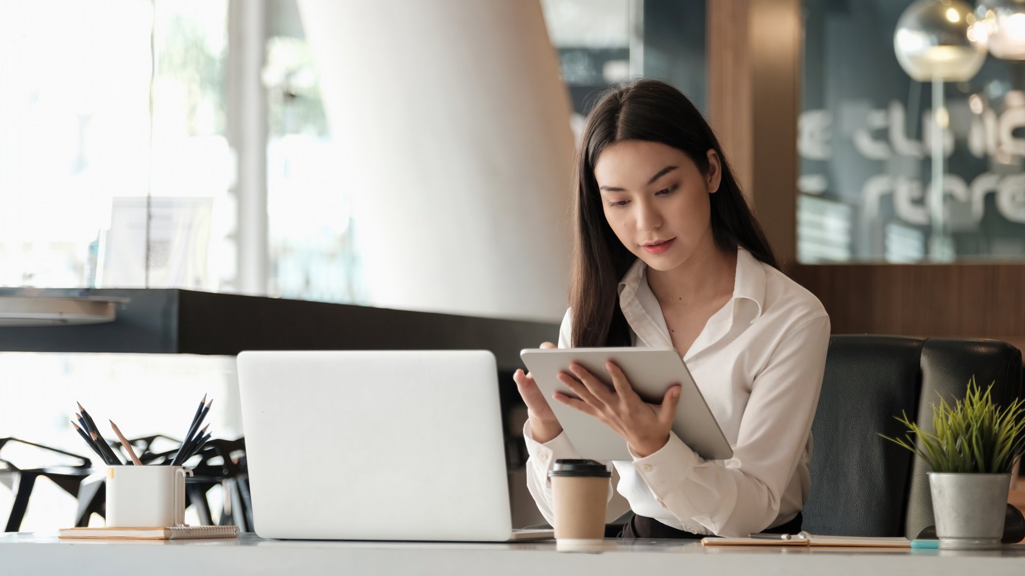 Beautiful business woman using tablet and laptop while working in the office.