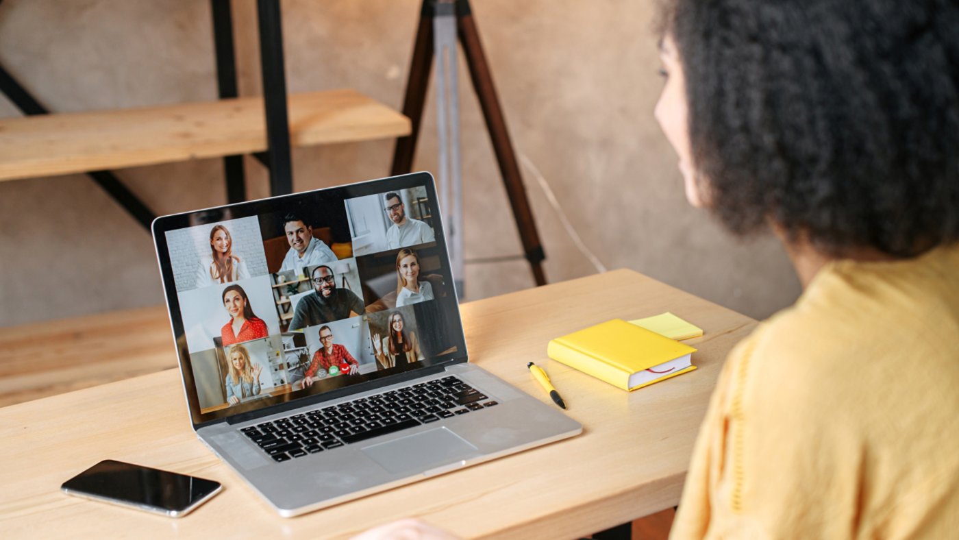 Virtual conference, online meeting. Mixed-race businesswoman using laptop app for communicating with several people at same time together. Video call with diverse multi-ethnic employees. Back view