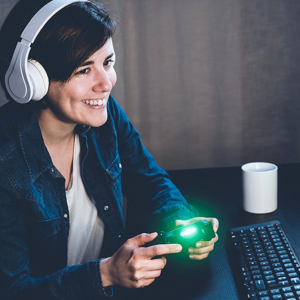 Gamer girl playing and streaming strategy video game online on twitch - Main focus on hand holding controller