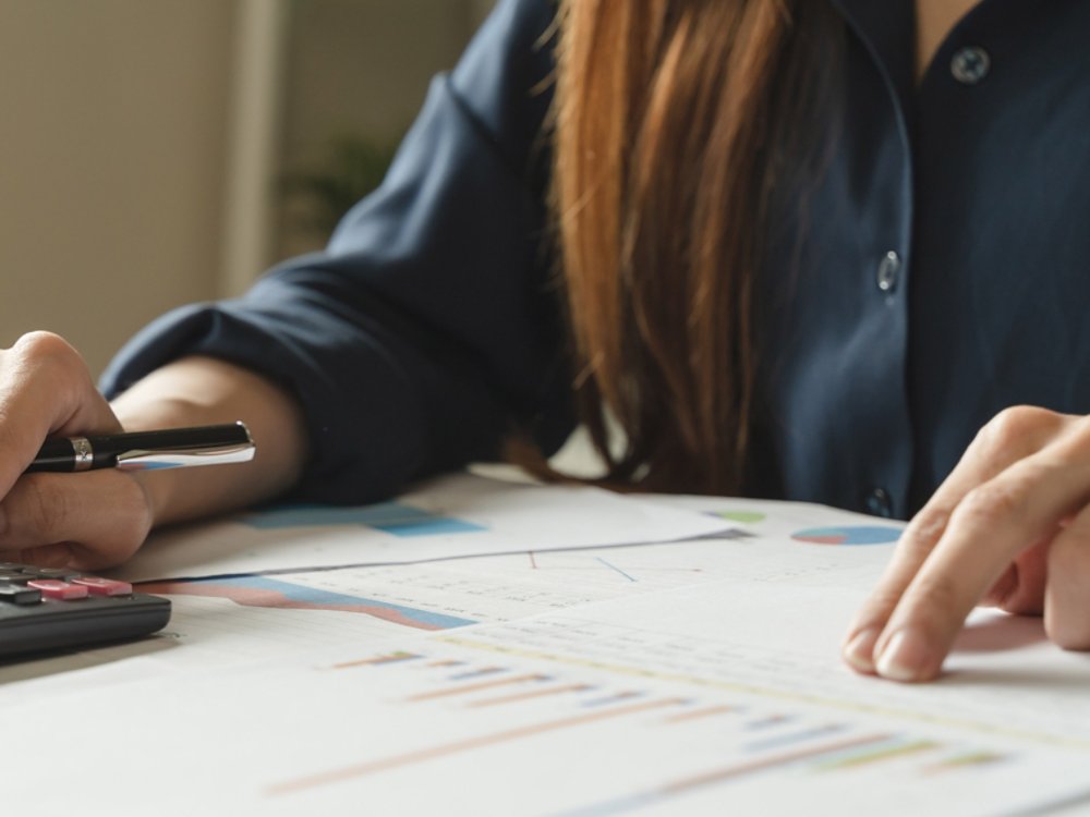 Women business people use calculators to calculate the company budget and income reports on the desk in the office.