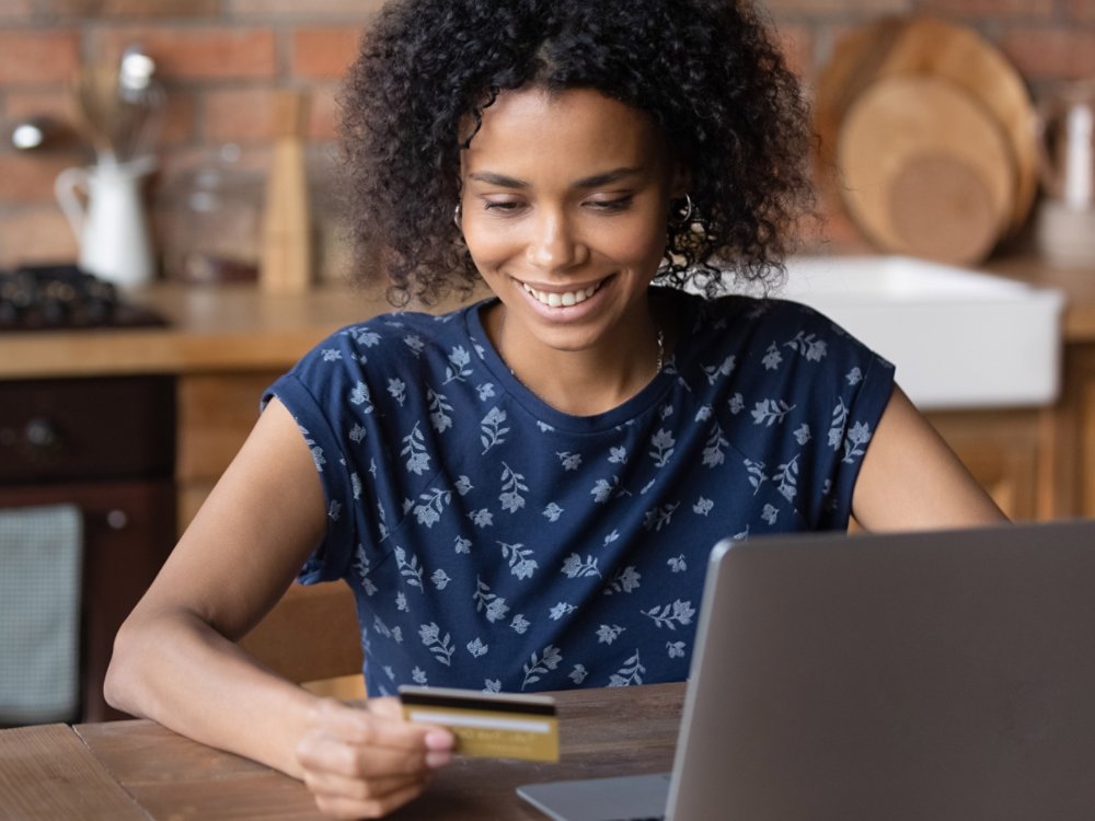 Smiling African American client customer buy purchase shop on internet paying online with credit card. Happy biracial woman make payment on laptop on web, use secure banking service system.