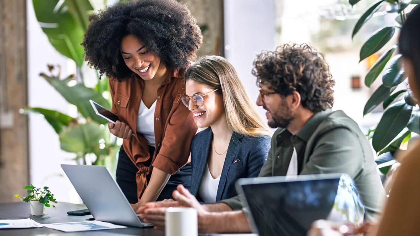 Smiling multiracial business colleagues discussing over laptop in office