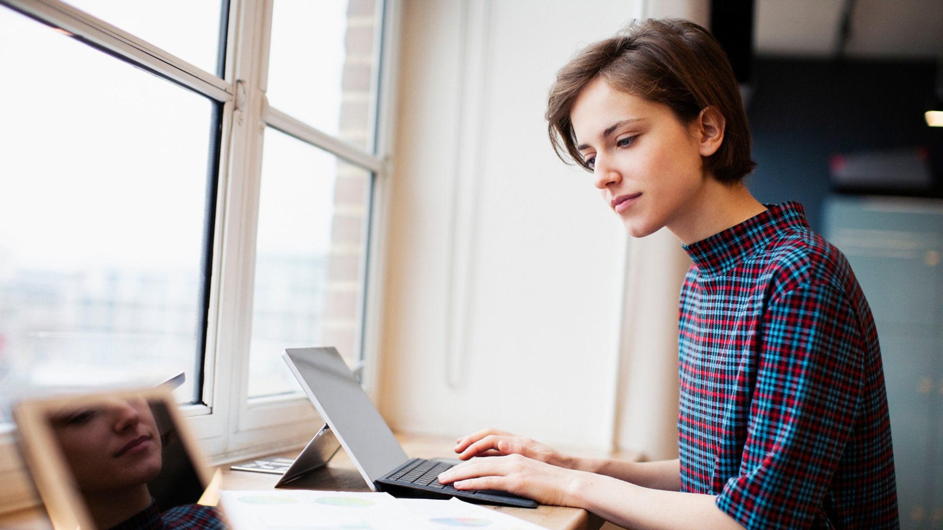 Businesswoman working at digital tablet in office window