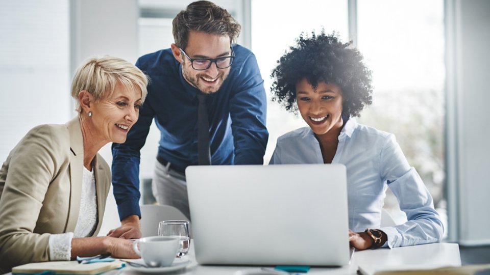 gathered group of businesspeople working together on a laptop