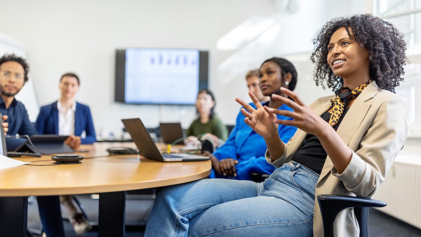 Businesswoman explaining her business plan to colleagues in a meeting. Female entrepreneur discussing a business strategy with team at startup office.