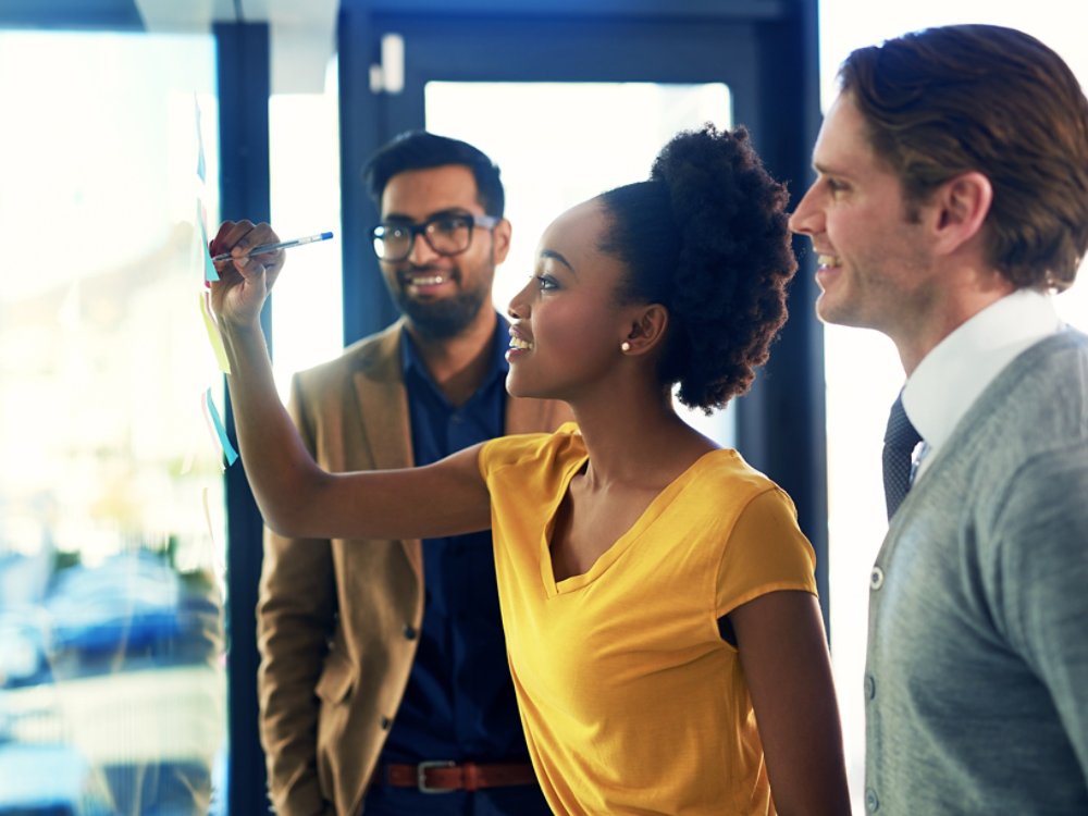 Cropped shot of a group of businesspeople brainstorming with notes on a glass wall in an office.