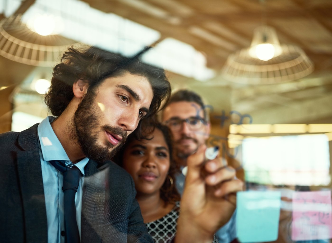 Cropped shot of coworkers using sticky notes on a glass wall during a meeting in the office.