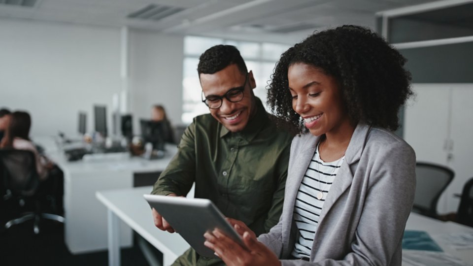 Professional young businesspeople using tablet computer smiling in office