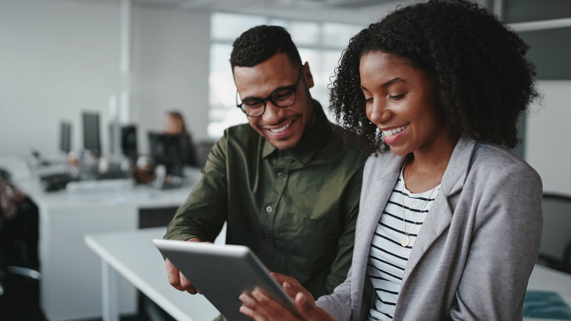 Professional young businesspeople using tablet computer smiling in office