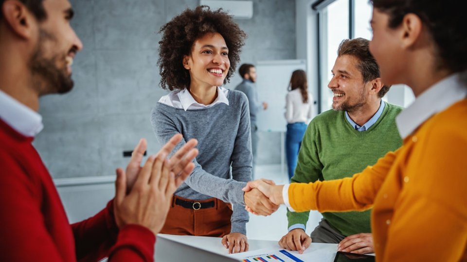 Diverse group of IT professionals congratulating one another and shaking hands