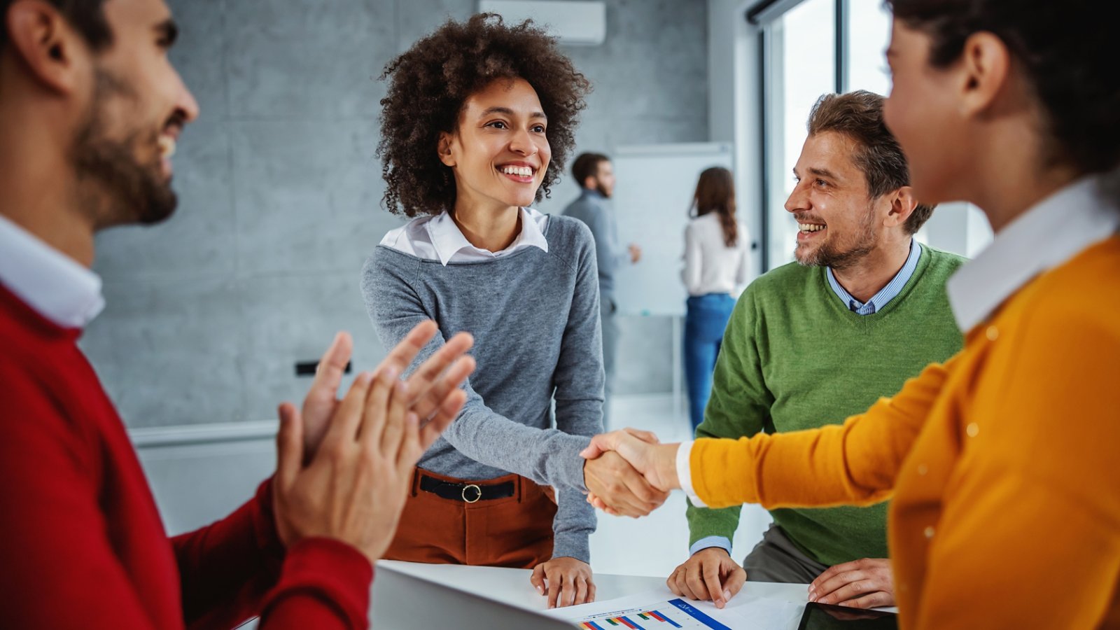 Diverse group of IT professionals congratulating one another and shaking hands