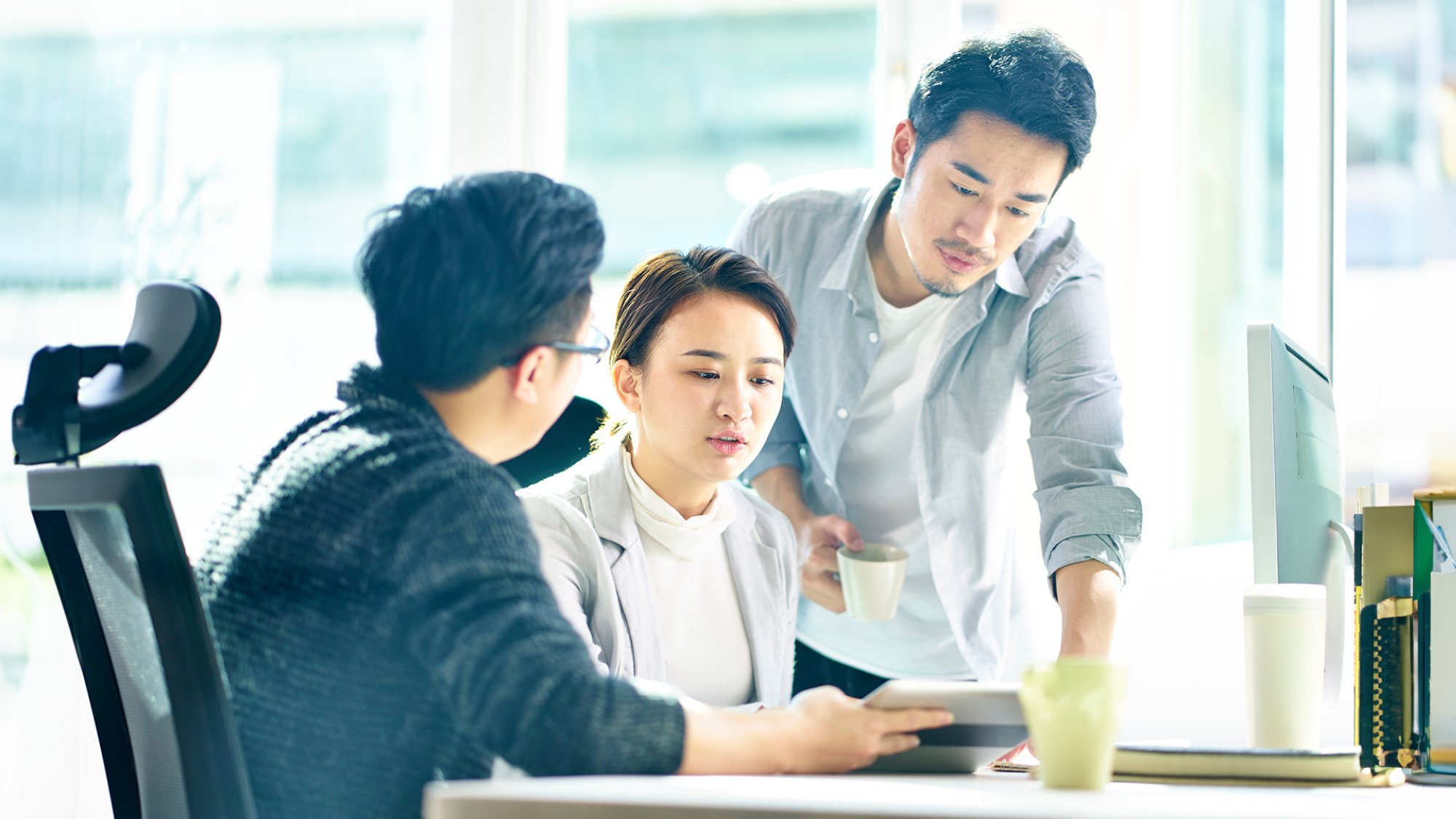 three young asian corporate executives working together discussing business plan in office.