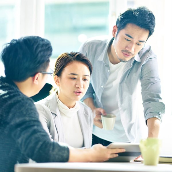 three young asian corporate executives working together discussing business plan in office.