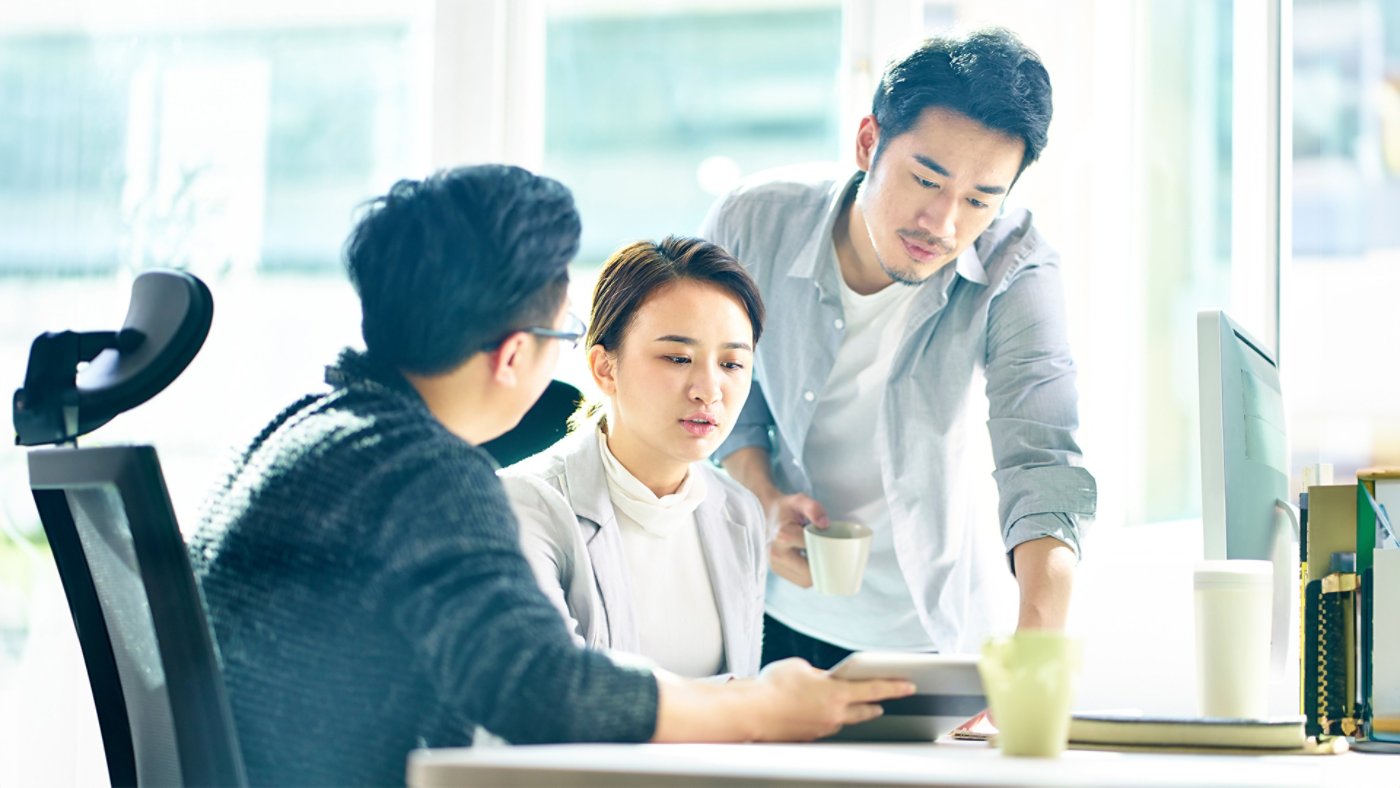 three young asian corporate executives working together discussing business plan in office.
