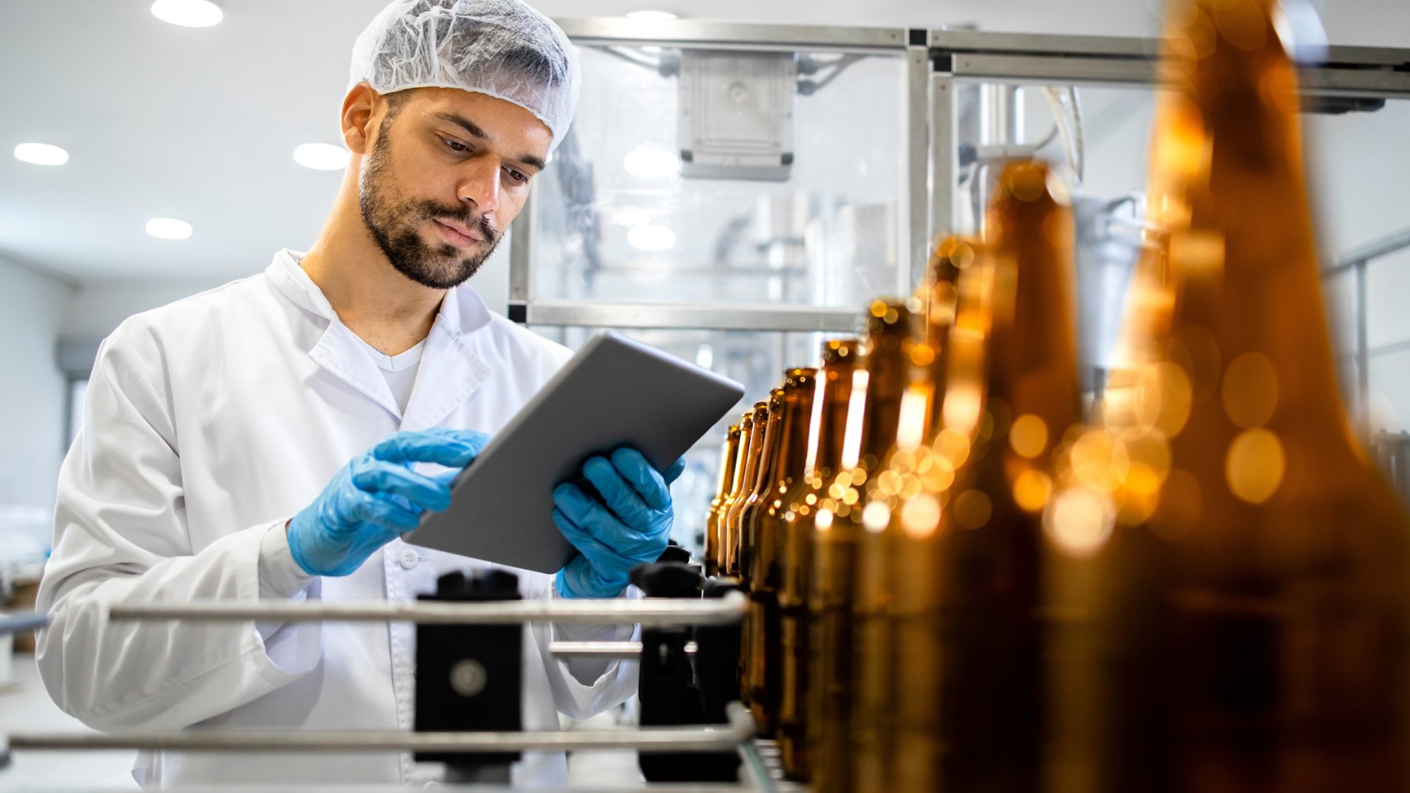 Bottled beer beverage production and factory worker controlling process on tablet computer.