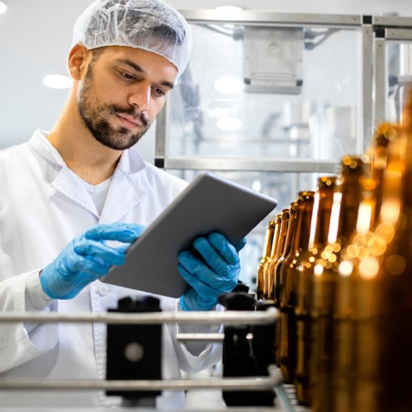 Bottled beer beverage production and factory worker controlling process on tablet computer.